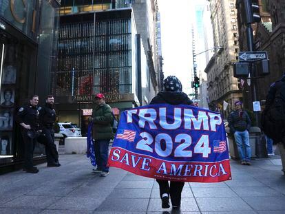Una mujer camina por la Quinta Avenida con una bandera de apoyo al expresidente Donald Trump, el martes en Nueva York.