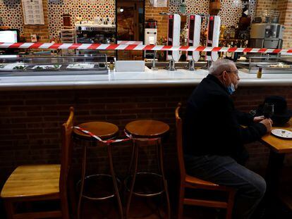 Man sits by a cordoned off bar counter at "Dominguez" restaurant in Madrid