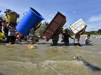 Colombianos deportados desde Venezuela cargan sus pertenencias a través del río Táchira.