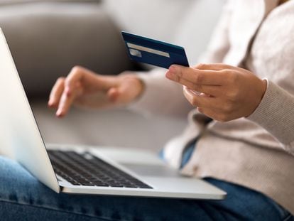 Close up woman shopping, paying by credit card, buying goods or ordering online, using laptop, login internet bank service, typing on keyboard, checking balance, sitting on sofa at home