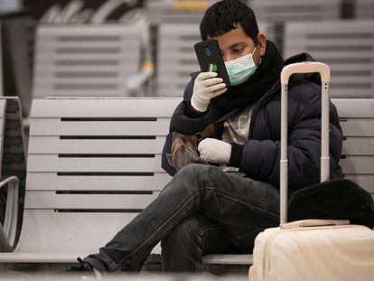 Un jove amb guants i mascareta a l'Estació de Sants, a Barcelona.
