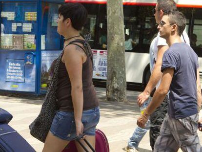 Varios turistas arrastran sus maletas hacia un hotel en las Ramblas de Barcelona.