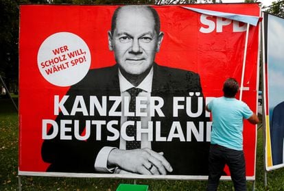 Un hombre pegaba este lunes en Bonn un cartel del candidato del SPD alemán, Olaf Scholz.