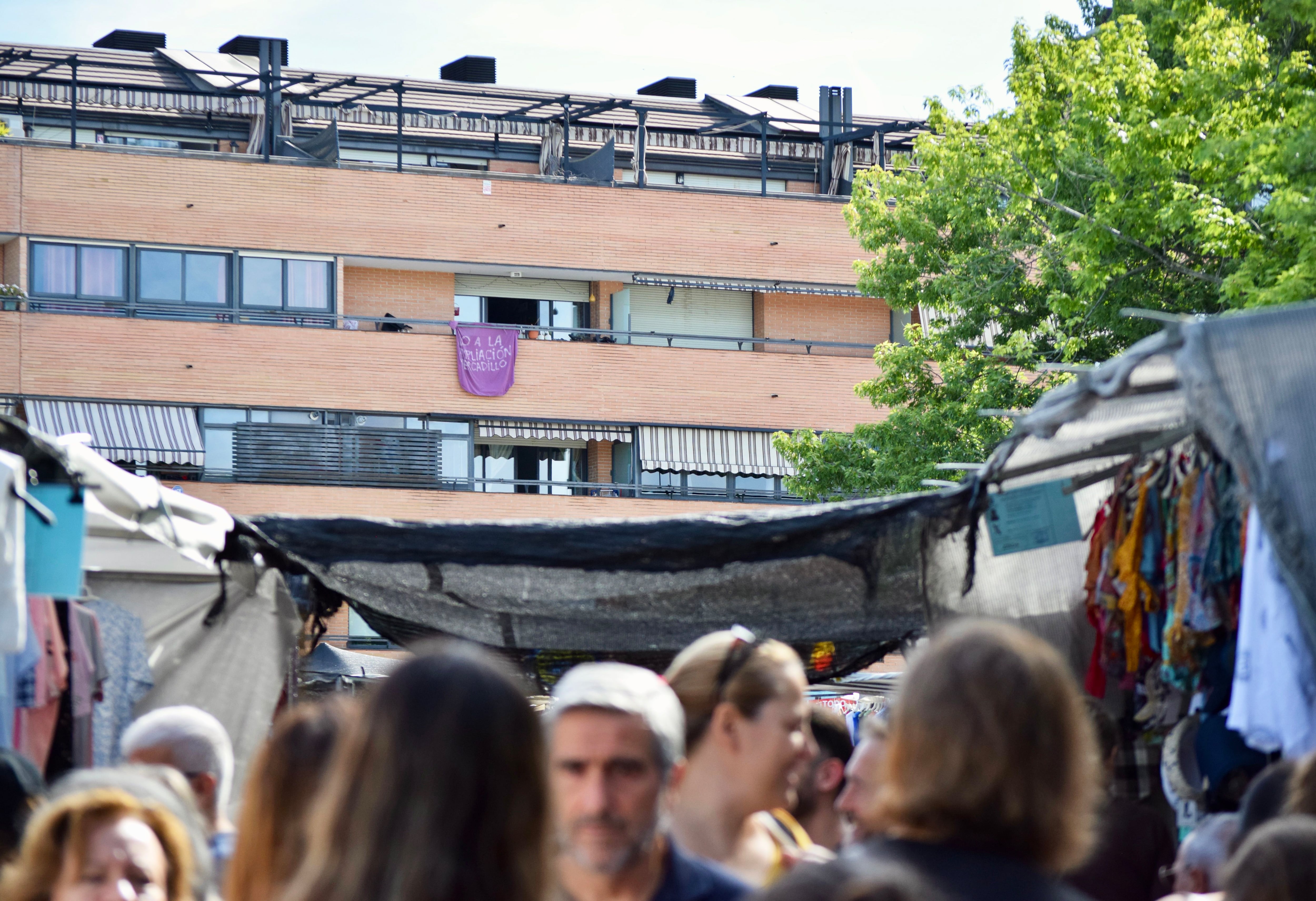 Desde el mercadillo de Majadahonda, se divisa en una lona morada con un mensaje de protesta: 