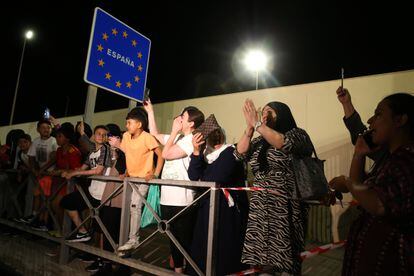 Varias personas apostadas junto a la frontera del Tarajal, en el lado español del límite entre España y Marruecos, la noche de este lunes. Las fronteras de Ceuta y Melilla han abierto este martes a la medianoche después de 26 meses cerradas. 