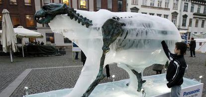 Un niño toca una escultura de hielo de un oso polar que se derrite.