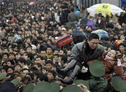 Los policías tratan de evacuar a una mujer enferma de entre la multitud que intenta entrar a la estación de tren de la ciudad de Guangzhou.