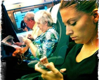 Una mujer lee el movil en el tren.