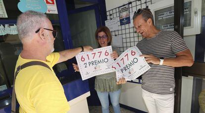 La titular de la administración de lotería nº 22 Los dos Patitos de Las Palmas de Gran Canaria, Mercedes Ramírez, y su marido Enrique Jiménez reciben los carteles por haber vendido el segundo premio.