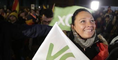 Una seguidora de Vox porta una bandera del partido ante la sede de la formación de ultraderecha, minutos después de conocerse los resultados electorales.
