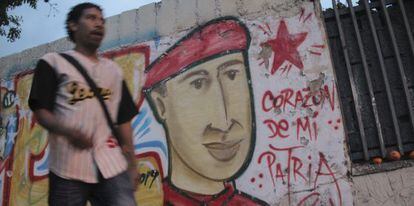 Un hombre camina por Caracas frente a la imagen de Ch&aacute;vez.