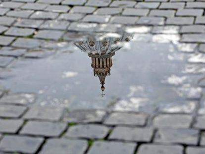 Vista de la cúpula de la basílica de San Pedro reflejada en un charco tras el anuncio de renuncia hecho por el papa Benedicto XVI.