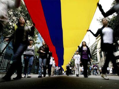 Los manifestantes sujetan una gran bandera colombiana durante la marcha en Bogotá.