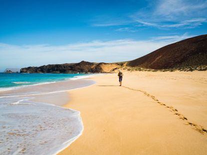 Senderista en la playa de Las Conchas, en la isla de La Graciosa, en Lanzarote.