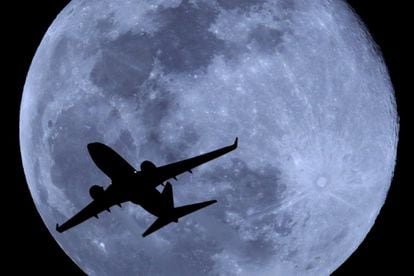 Un avión de pasajeros sobrevuela el cielo de Phoenix con la luna llena de fondo.