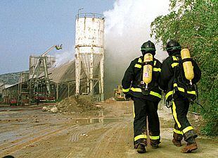 Dos bomberos se acercan al silo de la empresa Fertiberia, donde se produjo la nube contaminante.