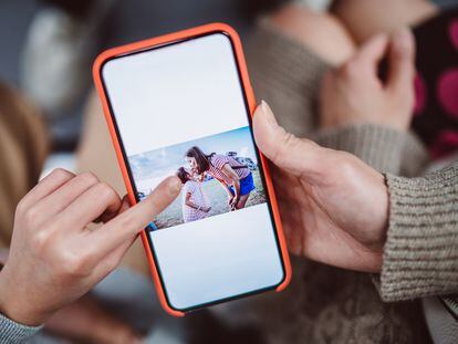 Una mujer mira una fotografía guardada en su teléfono móvil.