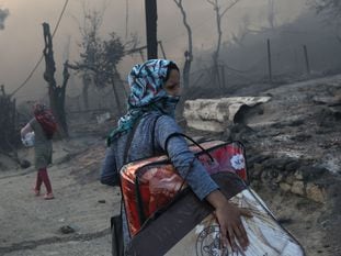 Una mujer traslada sus pertenencias tras el incendio, este miércoles. En vídeo, el incendio que ha arrasado el campo de refugiados de Moria.