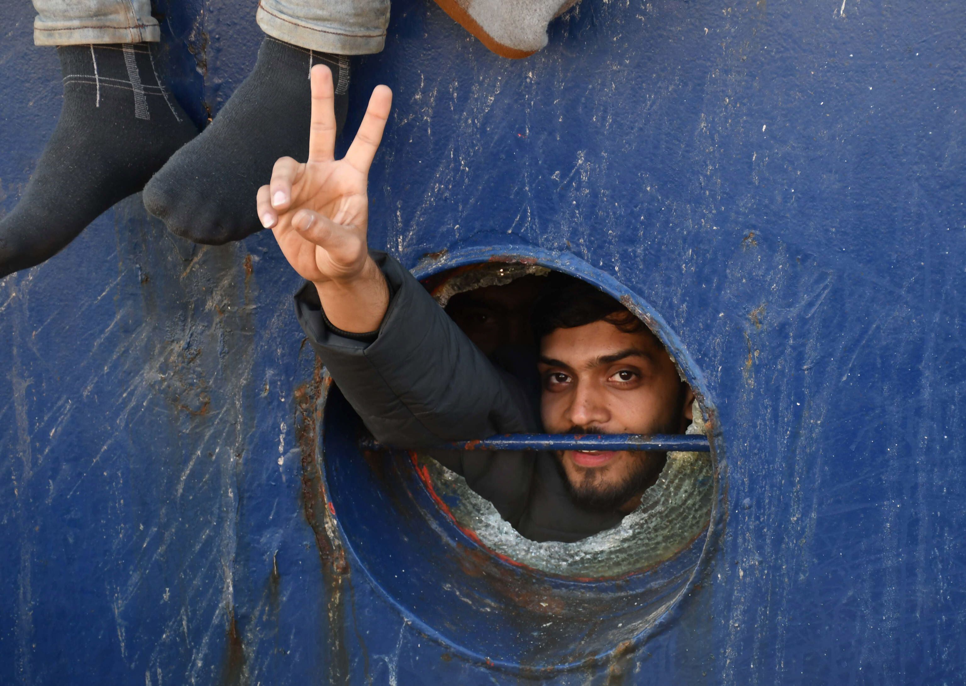 Un migrantes saluda desde el pesquero en el puerto de Catania.
