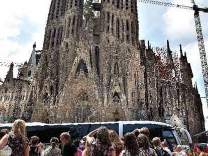 Turistas después de bajar de un autocar frente a la fachada del Nacimiento de la Sagrada Família.