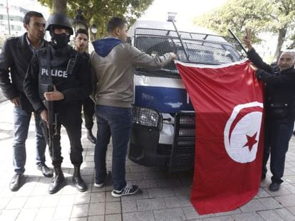 Dos homes ensenyen una bandera tunisiana al costat d'un policia, al centre de Tunis, aquest divendres.