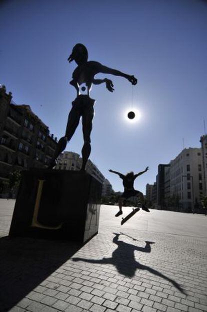 Un joven salta en monopatín junto a la estatua de Salvador Dalí, en la plaza Felipe II.