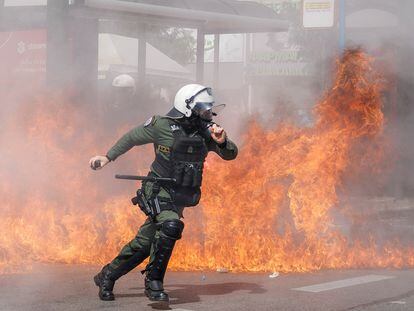 Un policía antidisturbios escapa del fuego provocado por los cócteles molotov lanzados por los manifestantes, este domingo cerca del Parlamento.