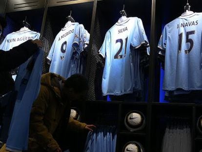 Dos aficionados observan las camisetas del Manchester City en la tienda oficial del club. 