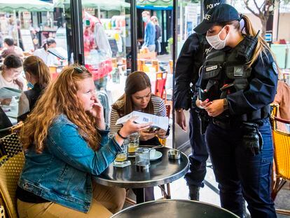 Una agente controla que los clientes de un bar en París poseen el certificado covid.