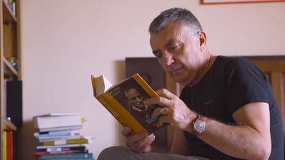 Manuel Vilas leyendo un libro de su biblioteca personal.