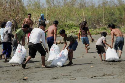 Supervivientes del tifón Haiyan cargan con víveres en la ciudad de Capiz.
