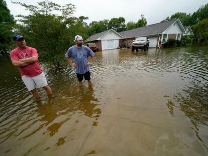 Danny González y Bob Neal atraviesan su vecindario inundado de agua después de pasar la tormenta tropical Claudette en Nueva Orleans.