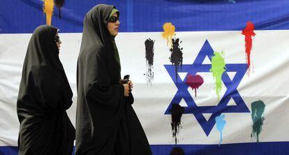 Un par de mujeres iraníes pasan delante de una bandera israelí durante una manifestación convocada para celebrar, hoy, el Día de Jerusalén.