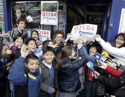 La propietaria de la administración de loteria nº 9 en el Paseo de Pereda en Santander, rodeada de niños, tras repartir 500.000 euros del tercer premio de la loteria nacional de navidad.