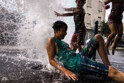 Unos niños se divierten mientras se refrescan en una boca de incendios abierta en Pantín, al norte de París (Francia).