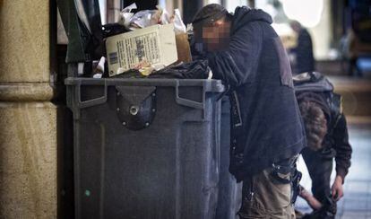 Una persona busca comida en un contenedor pr&oacute;ximo a un restaurante del centro de Barcelona