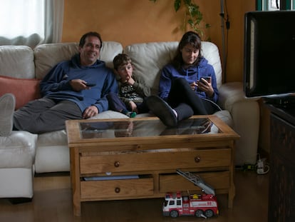 Una familia ve la televisión en el salón de su casa.