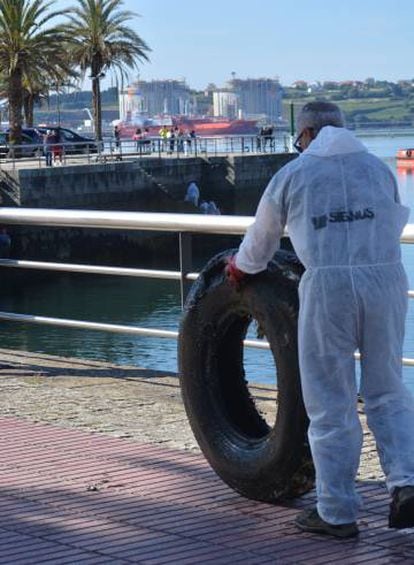 Un voluntario lleva una rueda sacada del mar en Ferrol el pasado junio.