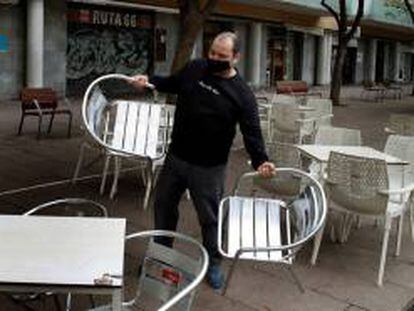 Un camarero prepara la terraza del restaurante donde trabaja para atender a sus clientes.