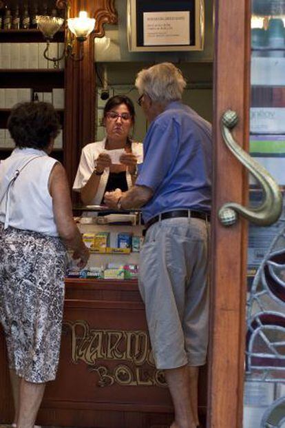 Una farmacéutica atiende a dos clientes en una farmacia de la calle Aragó de Barcelona