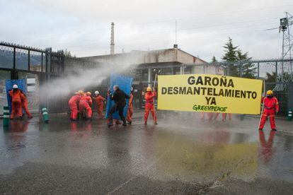 Un grupo de activistas despliega sus pancartas frente a la central tras simular su desmantelamiento.