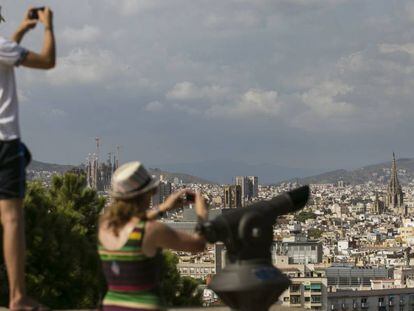 Dos turistas toman fotos de Barcelona desde Montjuic.
