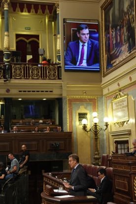Intervención de Alberto Núñez Feijóo en el atril mientras se proyecta la imagen del presidente del Gobierno en funciones, Pedro Sánchez.