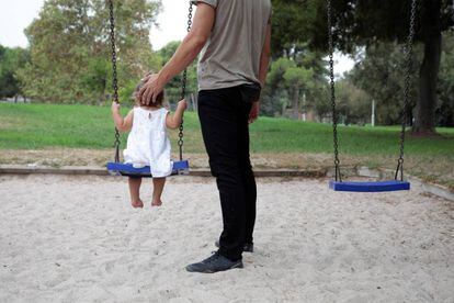 Un hombre juega con una niña en un columpio en Valencia.