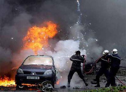 Tres bomberos sofocan el incendio que generó la explosión de un coche bomba en los recientes atentados de Argel, con nueve muertos.