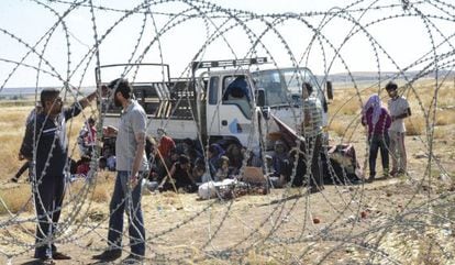 Varios kurdos esperan en la frontera turca después de haber escapado de Kobane (Siria).