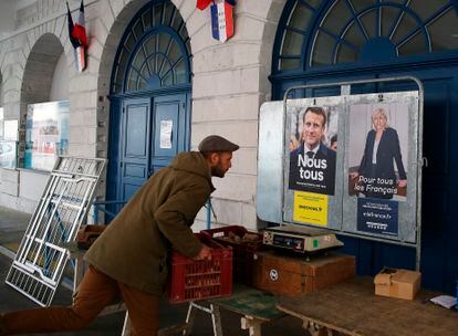 Un hombre coloca cajas de verduras delante de carteles electorales, este sábado en el mercado de Salies de Bearn, en el suroeste de Francia.