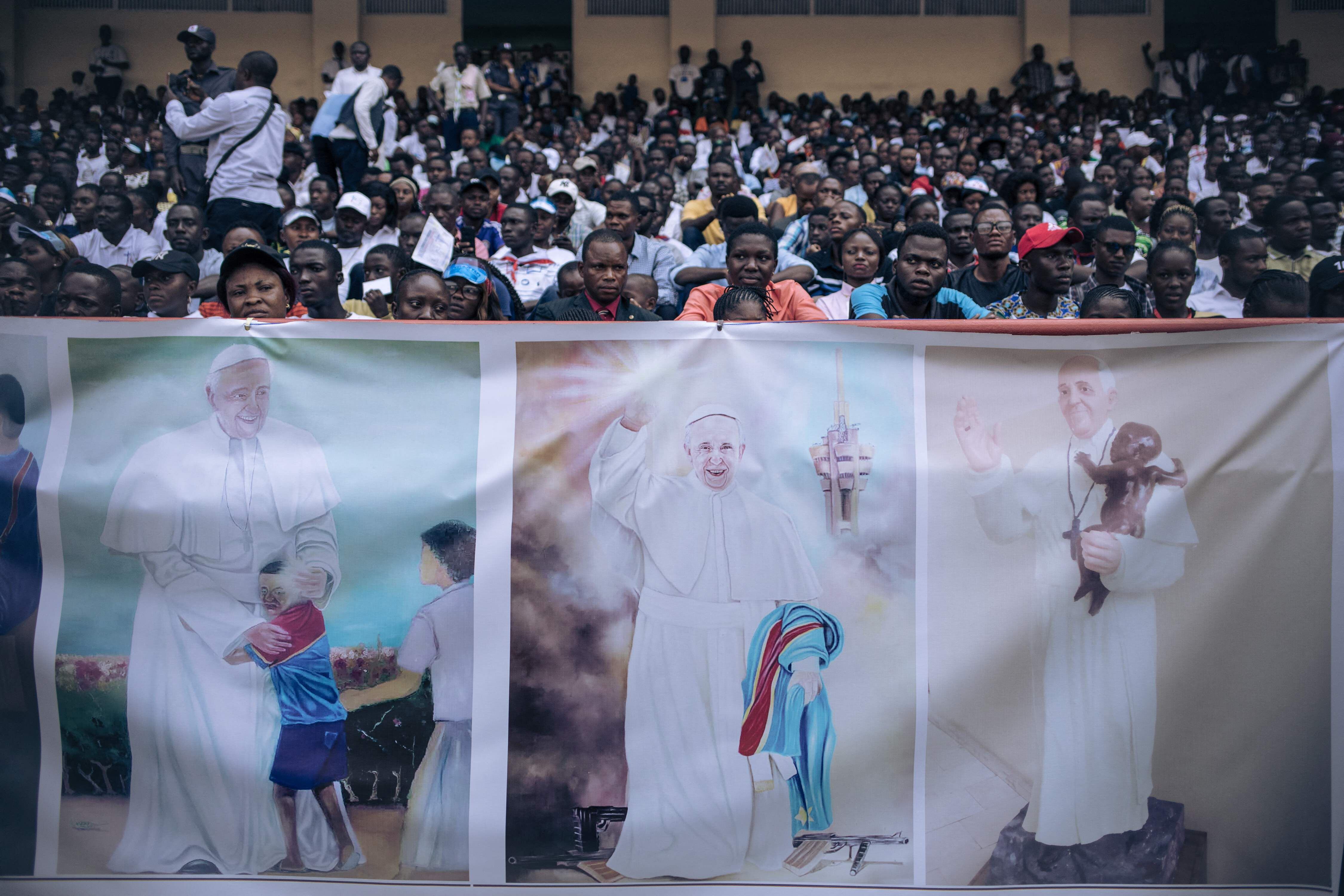 Los asistentes se sientan detrás de un cartel que refleja imágenes del papa Francisco, durante su evento este jueves en Kinsasa.