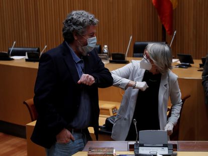 La periodista Gabriela Cañas, candidata a presidir Efe, saluda con el codo en el Congreso al diputado de Unidas Podemos Juan López de Uralde.