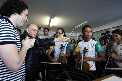 Gustavo Dudamel (izquierda) y José Antonio Abreu (a su lado) saludan a los jóvenes músicos que les acompañan en la gira latinoamericana. La fotografía está tomada en la favela Doña Marta de Río de Janeiro.
